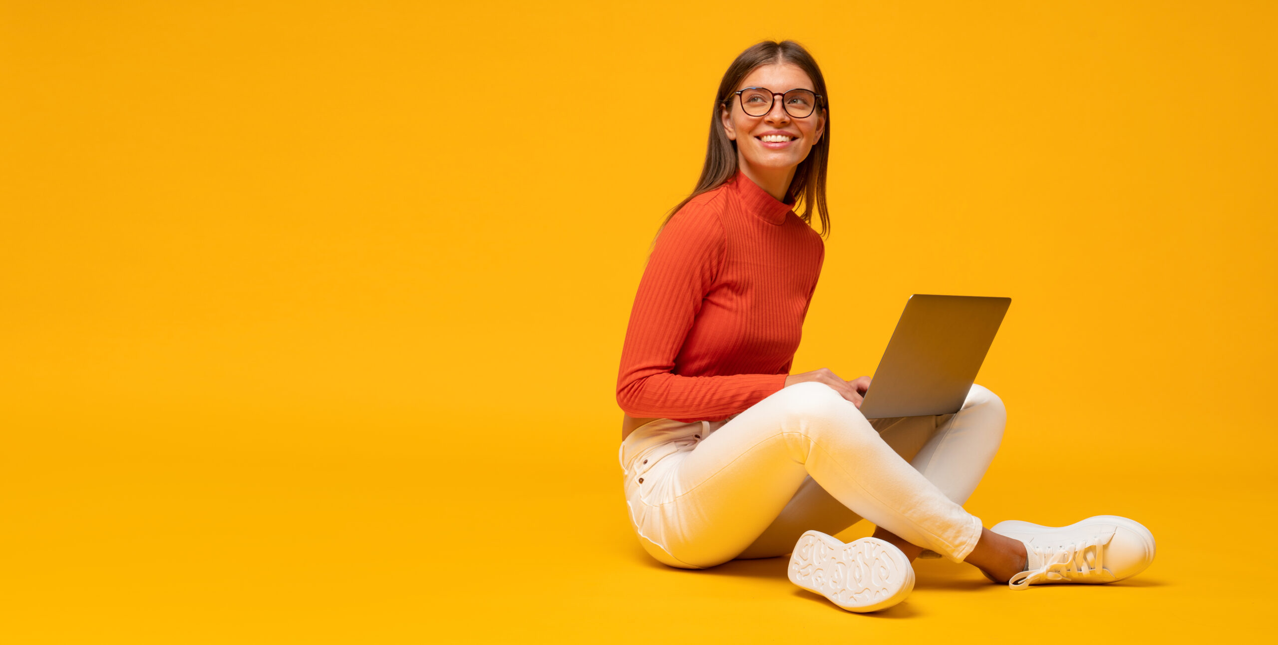 Banner of woman sitting on floor using laptop on yellow background with copy space on the right